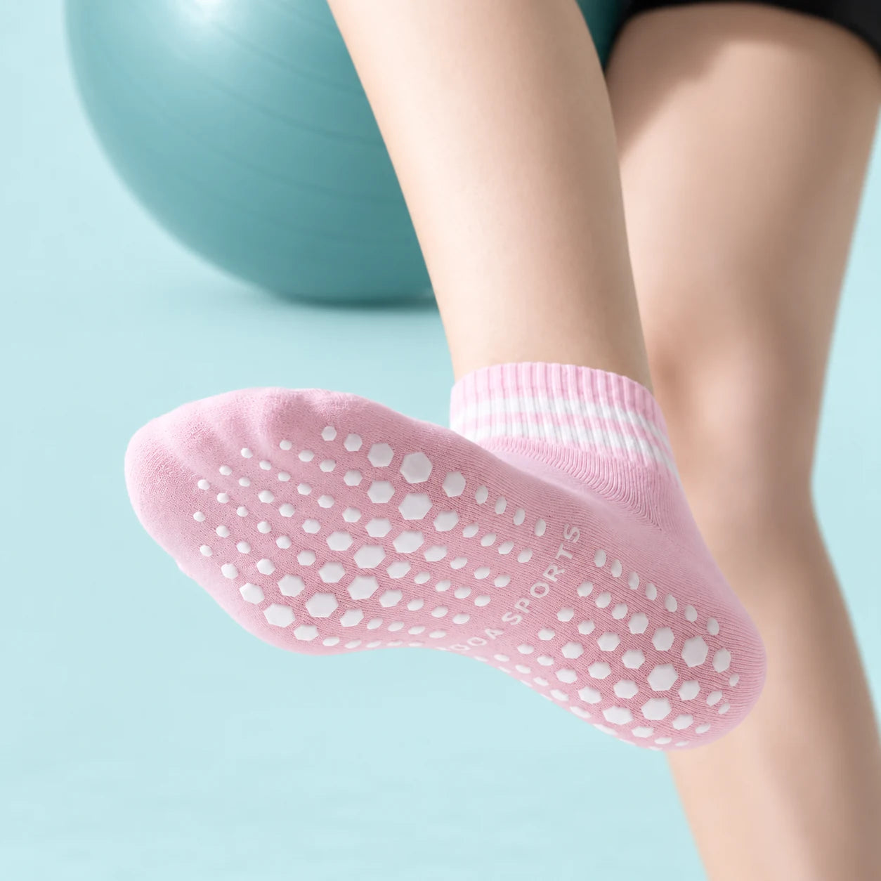 Pink ankle grip sock with a patterned non-slip sole on an exercise mat